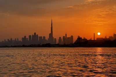 Dubaj látképe naplementekor, előtérben az öböl vizével